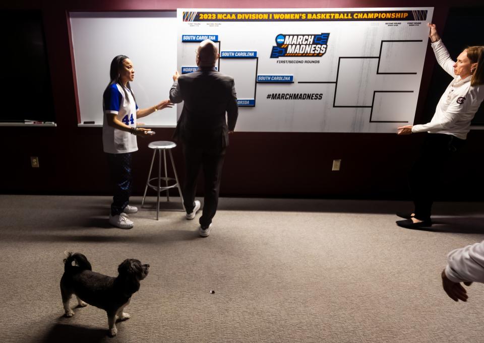 Mar 19, 2023; Columbia, SC, USA; South Carolina Gamecocks head coach Dawn Staley and her dog Champ watch as assistant coaches Fred Chmiel and Lisa Bower hang an updated bracket in the locker room following their 76-45 victory over the South Florida Bulls at Colonial Life Arena, advancing them to the Sweet 16. Mandatory Credit: Jeff Blake-USA TODAY Sports