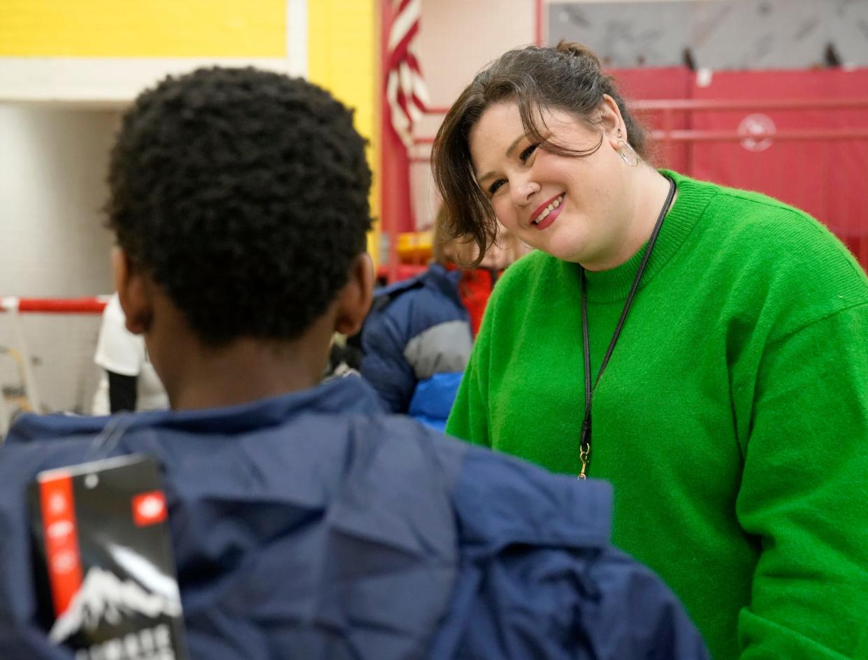 Amanda Hughes, a regional engagement coordinator for Columbus City Schools, helps a child try on winter coats during a distribution event at Burroughs Elementary School.