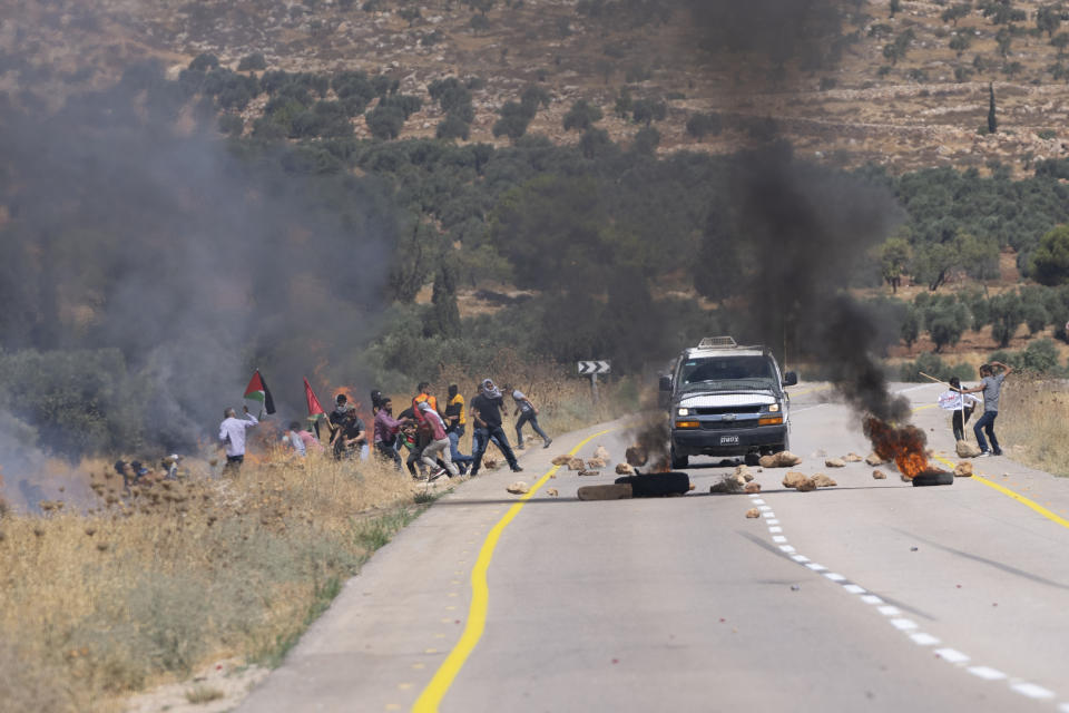 Israeli army troops use teargas canisters to disperse Palestinian protesters who burned tires and blocked the street that bypasses the West Bank village of Mughayer, north of Ramallah, Friday, July 29, 2022. Palestinians protesting against Israeli settlements activities blocked a main street and scuffled with Israeli settlers and army soldiers who used teargas to disperse them. (AP Photo/Nasser Nasser)