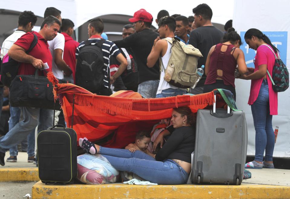 Venezuelan migrants rest while another group stands in line to enter an immigration office in Tumbes, Peru, Friday, June 14, 2019. Venezuelan citizens are rushing to enter Peru before the implementation of new entry requirements on migrants fleeing the crisis-wracked South American nation come into effect. (AP Photo/Martin Mejia)