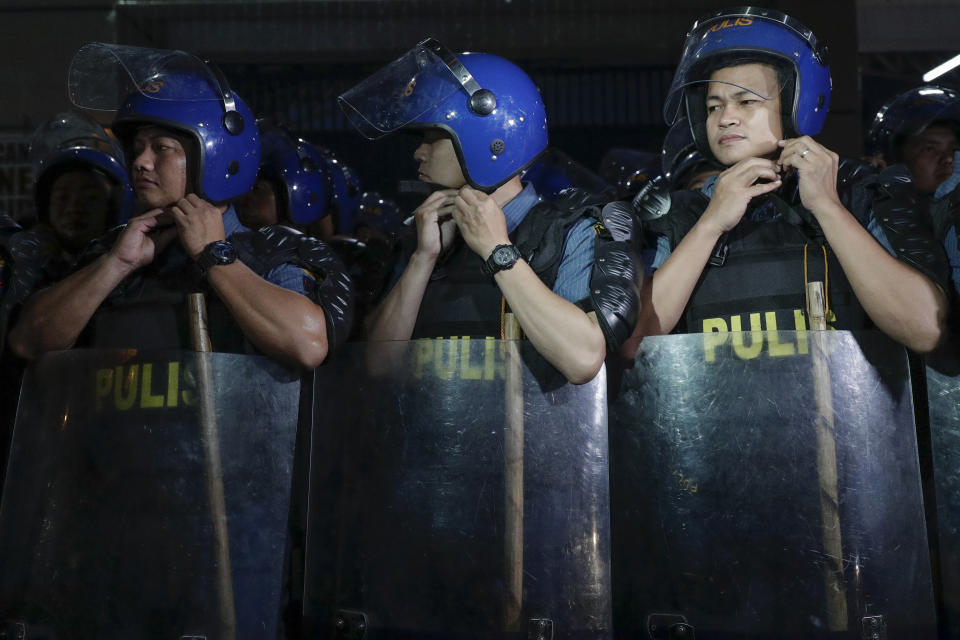 Policemen fix their helmets outside a court where a multiple murder case against scions of a political clan and their gunmen are set to be decided at Camp Bagong Diwa, Taguig city, Philippines, Thursday, Dec. 19, 2019. The Philippine court will rule Thursday whether scions of a political clan and their gunmen are guilty of slaughtering 58 people, including 32 media workers, in an act of impunity that horrified the world. (AP Photo/Aaron Favila)