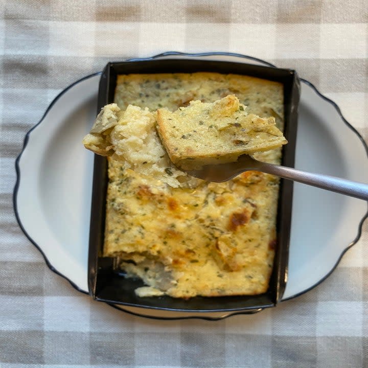 Aa close-up shot of the Artichoke Bread Pudding on a fork