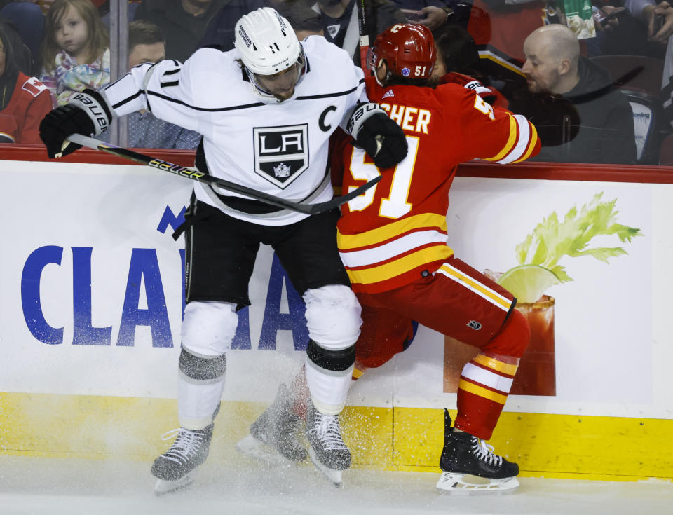 Los Angeles Kings forward Anze Kopitar, left, checks Calgary Flames defenseman Troy Stecher during the first period of an NHL hockey game Tuesday, March 28, 2023, in Calgary, Alberta. (Jeff McIntosh/The Canadian Press via AP)