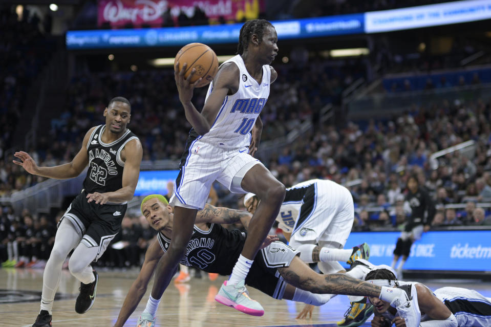 Orlando Magic center Bol Bol (10) drives to the basket past San Antonio Spurs guard Malaki Branham (22) and forward Jeremy Sochan (10) during the first half of an NBA basketball game Friday, Dec. 23, 2022, in Orlando, Fla. (AP Photo/Phelan M. Ebenhack)