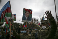 Azerbaijani soldiers hold national flags and portraits of Azerbaijani President Ilham Aliyev, left, and his father and former Azerbaijani President Heydar Aliyev, center, as they celebrate the transfer of the Lachin region to Azerbaijan's control, as part of a peace deal that required Armenian forces to cede the Azerbaijani territories they held outside Nagorno-Karabakh, in Aghjabadi, Azerbaijan, Tuesday, Dec. 1, 2020. Azerbaijan has completed the return of territory ceded by Armenia under a Russia-brokered peace deal that ended six weeks of fierce fighting over Nagorno-Karabakh. Azerbaijani President Ilham Aliyev hailed the restoration of control over the Lachin region and other territories as a historic achievement. (AP Photo/Emrah Gurel