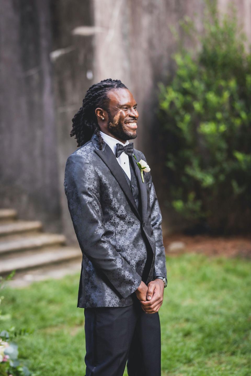 A groom smiles as his bride walks towards him during their wedding ceremony.