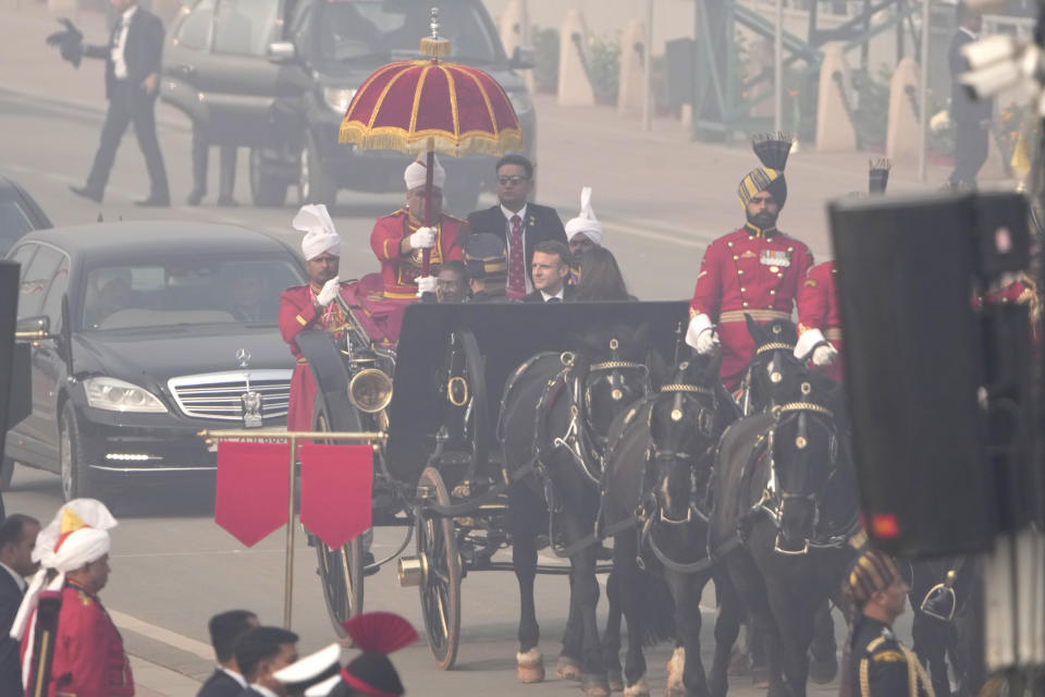 Indian President Droupadi Murmu with her French counterpart Emmanuel Macron arrive in a ceremonial British-era horse-drawn carriage for the Republic day parade in New Delhi, India, Friday, Jan. 26, 2024. Thousands of people cheer a colorful parade showcasing India's defense capability and cultural heritage braving a winter chill and mist on a ceremonial boulevard in the Indian capital. (AP Photo/Manish Swarup)