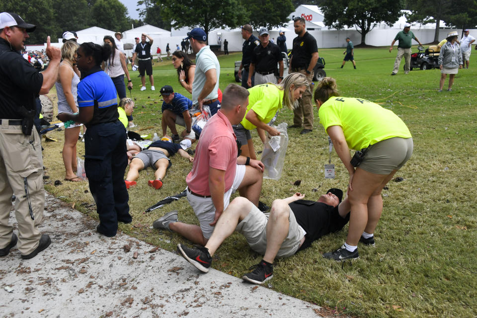 Spectators are tended to after a lightning strike on the course left several injured during a weather delay in the third round of the Tour Championship golf tournament Saturday, Aug. 24, 2019, in Atlanta. (AP Photo/John Amis)