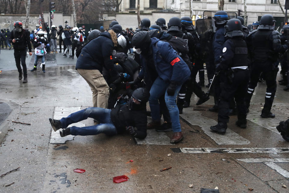 A police officer helps a colleague falling during clashes after a yellow vest demonstration Saturday, Jan. 19, 2019 in Paris. Yellow vest protesters are planning rallies in several French cities despite a national debate launched this week by President Emmanuel Macron aimed at assuaging their anger. (AP Photo/Thibault Camus)