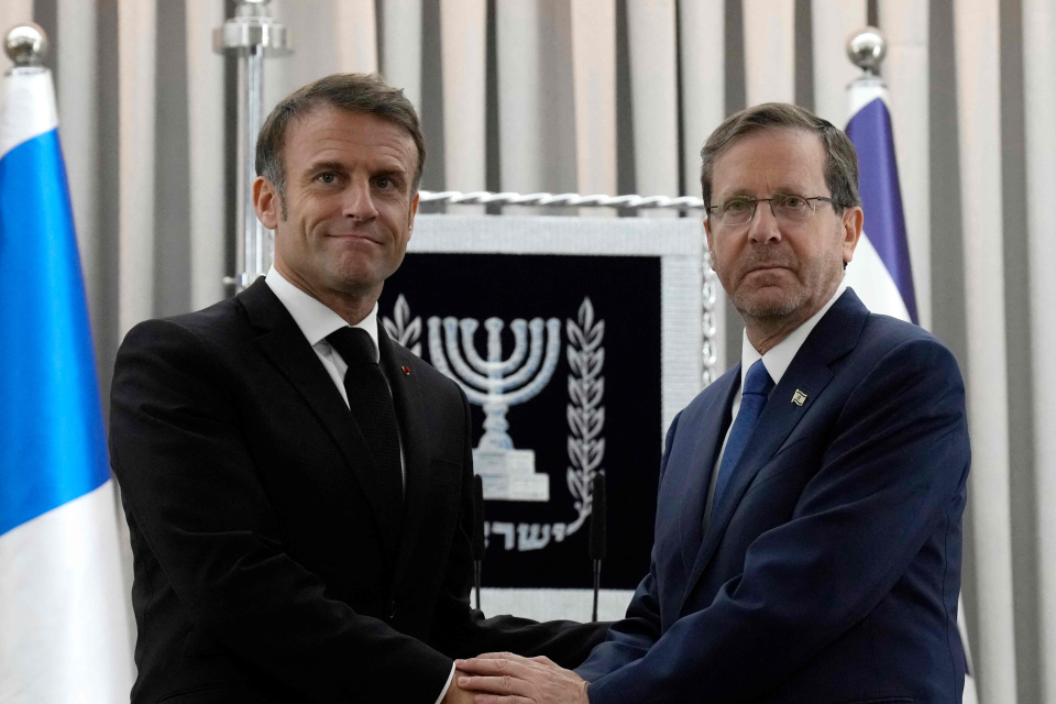 Mr Macron shakes hands with Israel's President Isaac Herzog in Jerusalem (POOL/AFP via Getty Images)