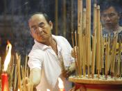 A man lights joss sticks during the Hungry Ghost festival in Kuala Lumpur August 3, 2014. According to Taoist and Buddhist beliefs, the seventh month of the Chinese Lunar calendar, known as the Hungry Ghost Festival is when the Gates of Hell open to let out spirits who wander the land of the living looking for food. Food offerings are made while paper money and joss sticks are burnt to keep the spirits of dead ancestors happy and to bring good luck. REUTERS/Olivia Harris (MALAYSIA - Tags: SOCIETY RELIGION)