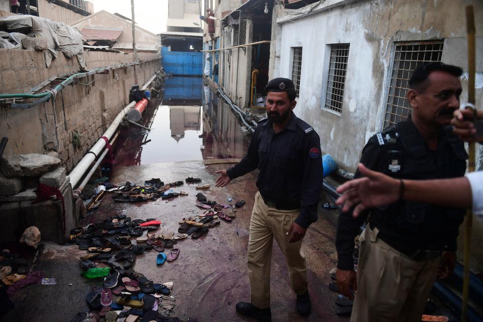 Police officers stands next to footwear of victims following a stampede that ocurred during a Ramadan alms distribution for people in need, in Karachi on March 31, 2023. - At least nine people were killed in a crowd crush in Pakistan's southern city of Karachi on March 31 as a Ramadan alms donation sparked a stampede in the inflation-hit nation, officials said. (Photo by Asif HASSAN / AFP) (Photo by ASIF HASSAN/AFP via Getty Images)