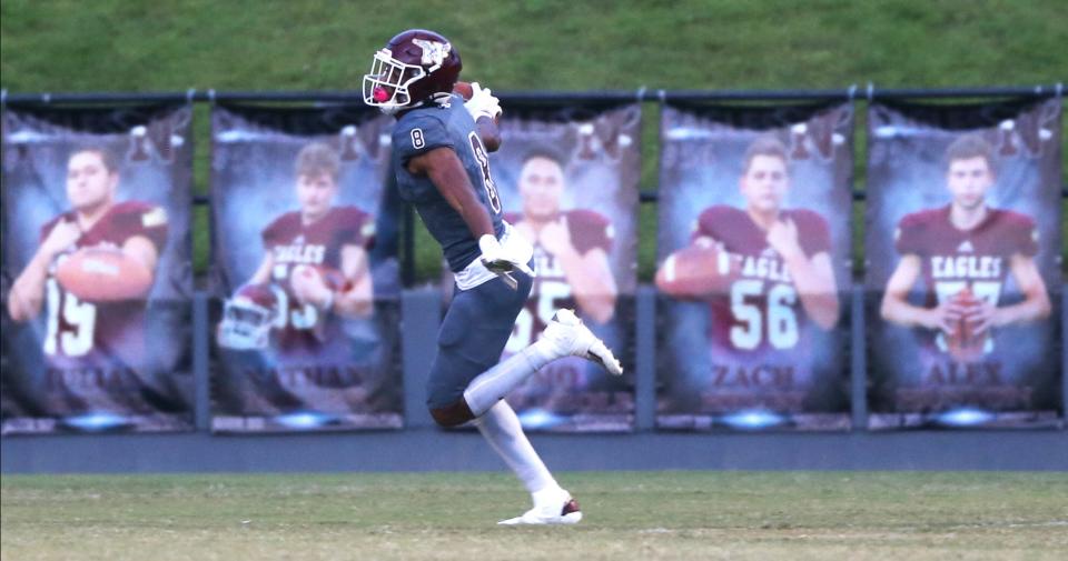 Azareyeh Thomas soars past pictures of his team after scoring during the Niceville Mosley football game at Niceville.