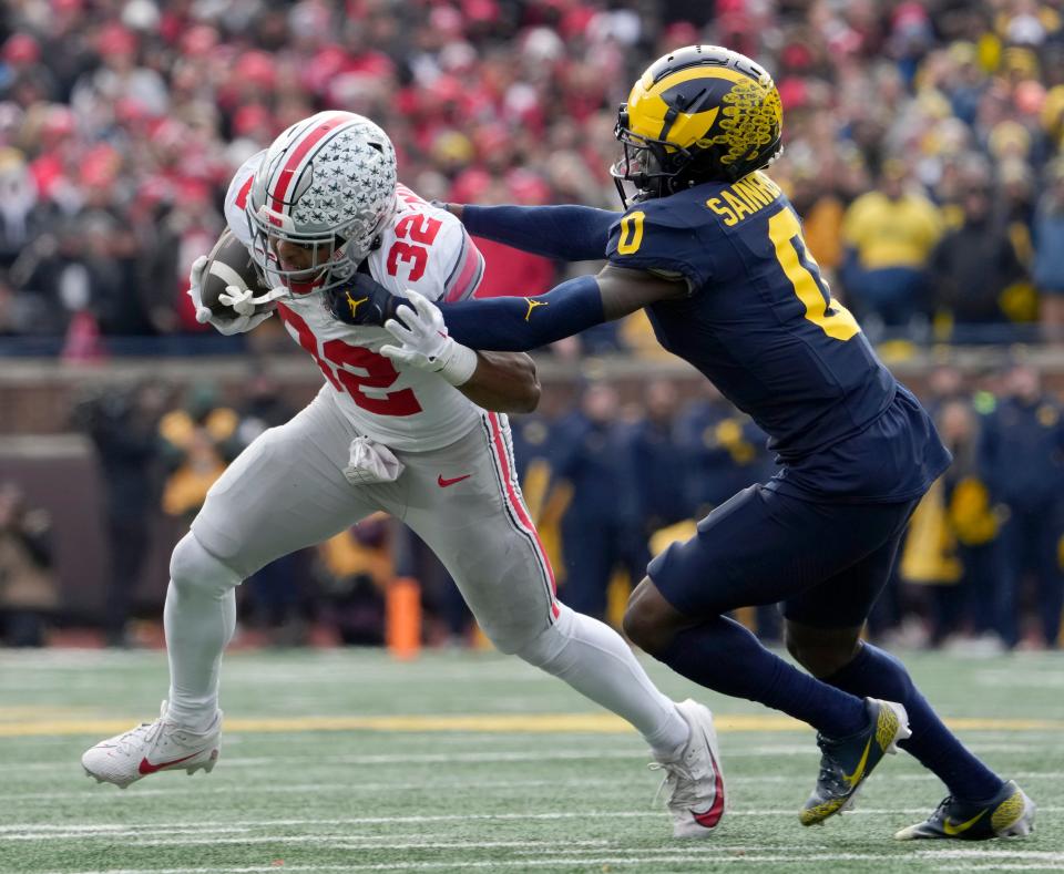 Ohio State running back TreVeyon Henderson is tackled by Michigan defensive back Mike Sainristil during the Buckeyes' 30-24 loss in Ann Arbor.