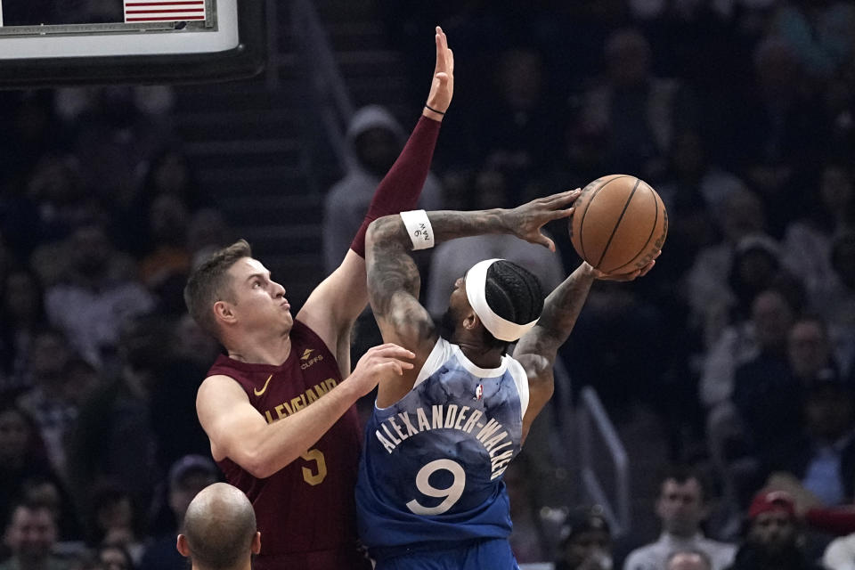 Minnesota Timberwolves guard Nickeil Alexander-Walker (9) shoots as Cleveland Cavaliers guard Sam Merrill (5) defends during the first half of an NBA basketball game Friday, March 8, 2024, in Cleveland. (AP Photo/Sue Ogrocki)