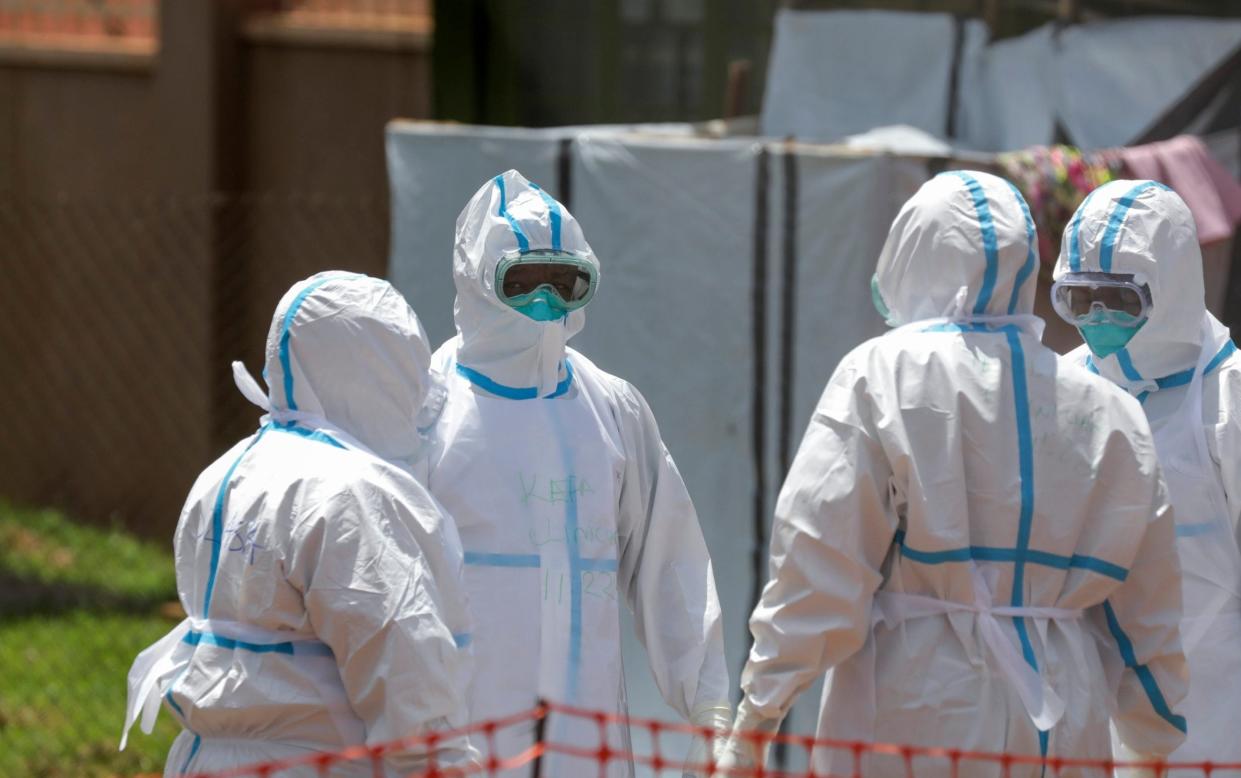 Doctors stand in a circle to say a prayer before entering the Ebola isolation section of Mubende Regional Referral Hospital, in Mubende, Uganda