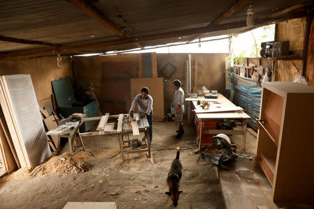 Edgar Champi (L), a resident of Nueva Union shantytown who plays soccer at a makeshift soccer field, works at his carpentry workshop in Villa Maria del Triunfo district of Lima, Peru, May 4, 2018. REUTERS/Mariana Bazo