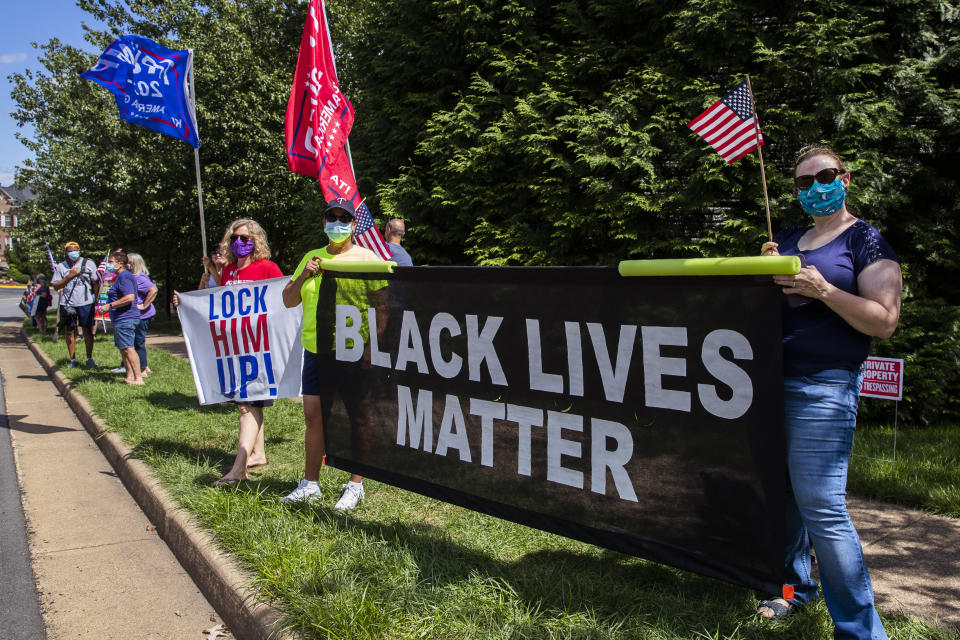 Supporters of President Donald Trump and protesters hold banners as they wait for the motorcade of President Trump outside the Trump National Golf Club in Sterling, Va., Sunday, Aug. 30, 2020. (AP Photo/Manuel Balce Ceneta)