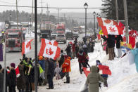 Protesters and supporters against a COVID-19 vaccine mandate for cross-border truckers cheer as a parade of trucks and vehicles pass through Kakabeka Falls outside of Thunder Bay, Ontario, on Wednesday, Jan. 26, 2022. (David Jackson/The Canadian Press via AP)