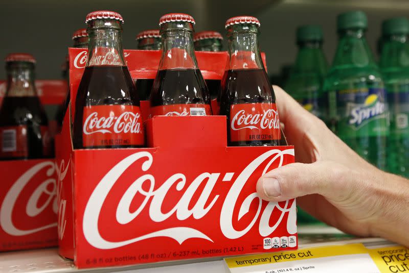 FILE PHOTO: An employee arranges bottles of Coca-Cola at a store in Alexandria