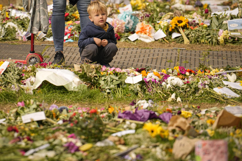 People bring floral tributes to Queen Elizabeth II, the day after her funeral in London's Green Park, Tuesday, Sept. 20, 2022. The Queen, who died aged 96 on Sept. 8, was buried at Windsor alongside her late husband, Prince Philip, who died last year. (AP Photo/Vadim Ghirda)