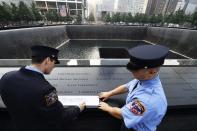 New York Fire Department firefighters Andrew Esposito (L) and his brother Michael Esposito make a rubbing of their father's name, Michael A. Esposito, at the South reflecting pool at the 9/11 Memorial during ceremonies marking the 12th anniversary of the 9/11 attacks on the World Trade Center in New York, September 11, 2013. (REUTERS/Stan Honda/Pool)