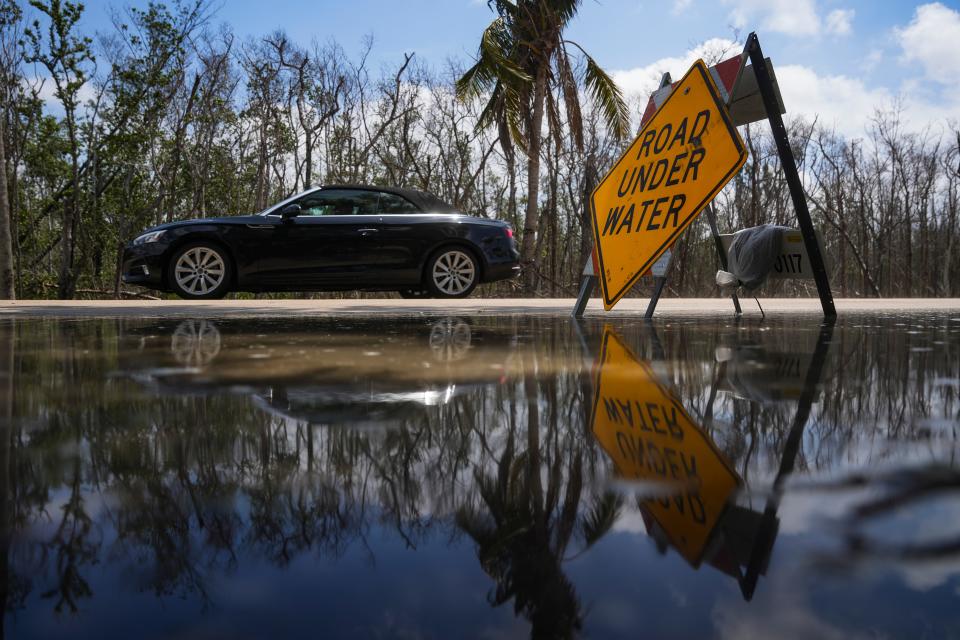 A car drives past a sign on Hickory Boulevard warning of water on the roadway after Hurricane Idalia at Bonita Beach on Wednesday, Aug. 30, 2023.
