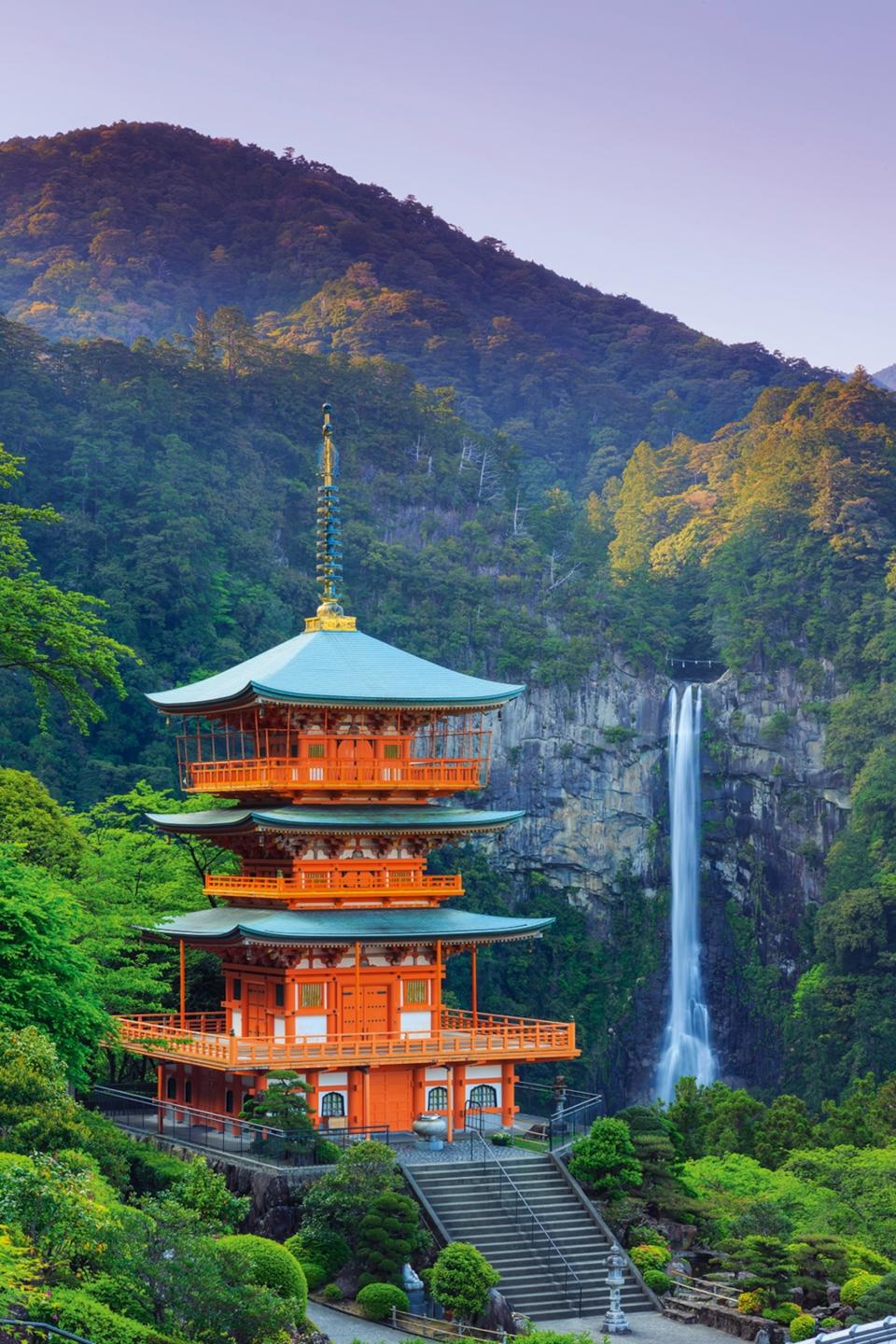 Red pagoda three-storied temple stood next to a waterfall in the mountains