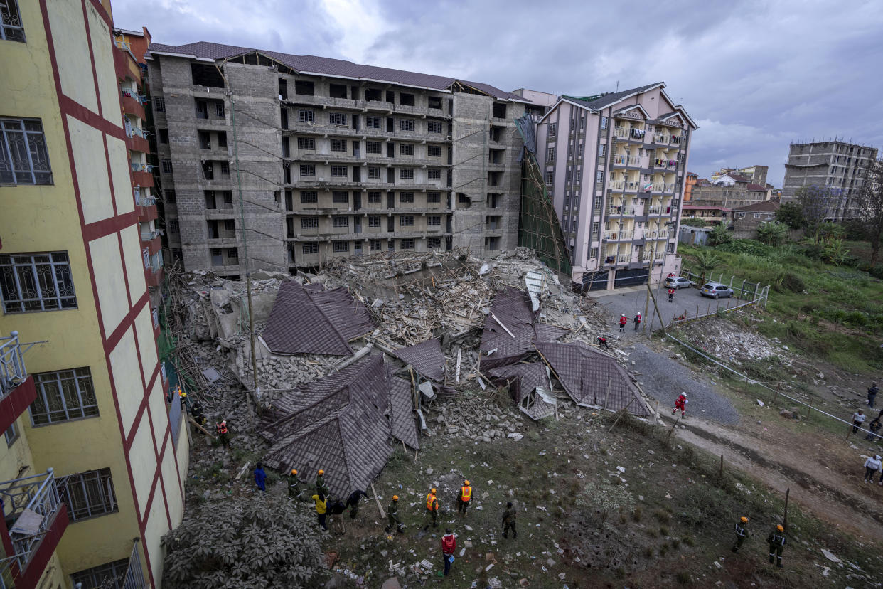 Rescue workers gather at the scene of a building collapse in the Kasarani neighborhood of Nairobi, Kenya Tuesday, Nov. 15, 2022. Workers at the multi-storey residential building that was under construction are feared trapped in the rubble and rescue operations have begun, but there was no immediate official word on any casualties. (AP Photo/Ben Curtis)