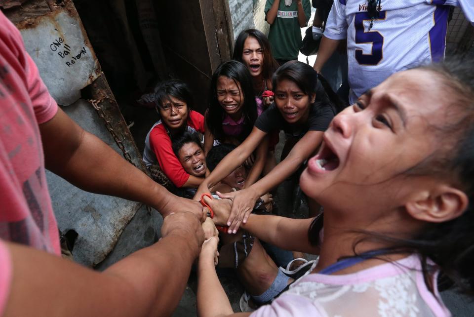 epa04044201 Filipino resident Brix Mercado, 27, (C) is being shielded by his family to prevent the local police from arresting him during a demolition of shanties at Sitio San Roque in Quezon City, east of Manila, Philippines, 27 January 2014. Throwing rocks, pillboxes, and even human waste, illegal settlers barricaded the demolition team in Baranggay Bagong Pag-asa. Four residents were arrested and twelve were reported injured. Residents report receiving cash from 300 to 450 US dollar in exchange for their voluntary relocation. Earlier, hundreds of the urban poor marched to the city hall in protest of the demolition that will pave the way for the rise of a business district. EPA/DENNIS M. SABANGAN