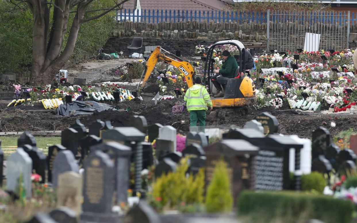Workers use machinery to dig graves in Bradford, West Yorkshire, where it was reported that services struggled to keep up with the number of burials due to coronavirus - Danny Lawson/PA