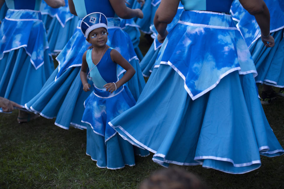 A young performer stands with her troupe during the "Tambores de Olokun" street party in Rio de Janeiro, Brazil, Saturday, Feb. 15, 2020. Thousands have started attending the popular street parties ahead of the world's famous carnival festival that begins on Feb 21. (AP Photo/Silvia Izquierdo)