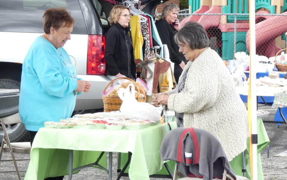 Sandy Bray, right, purchases baked goods from Marci Teynor during the Dutchtown Farmers Market in New Washington on Thursday.