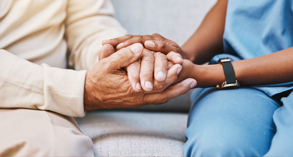 Aged care worker holding hands with an elderly person