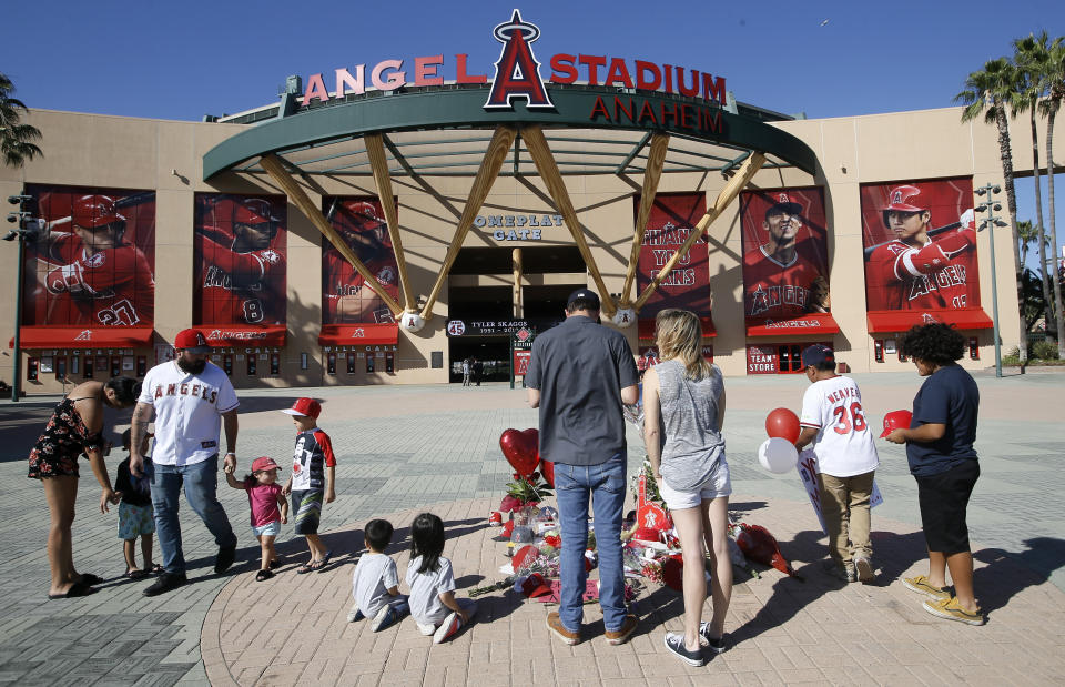 Mourners stand at a memorial to give their condolences for Los Angeles Angels pitcher Tyler Skaggs at Angel Stadium in Anaheim, Calif., Monday, July 1, 2019. Skaggs died at the age of 27, stunning Major League Baseball and leading to the postponement of the team's game against the Texas Rangers on Monday. (AP Photo/Alex Gallardo)