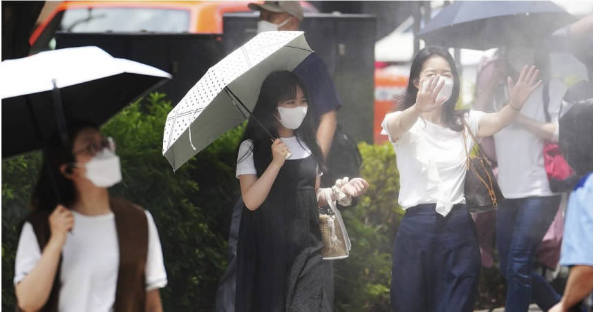 東京已連續9天出現超過35度的高溫。東京的千代田區有行人主動迎向路邊的噴霧器來降溫，許多人則撐起陽傘抵擋酷暑。（圖／達志／美聯社）