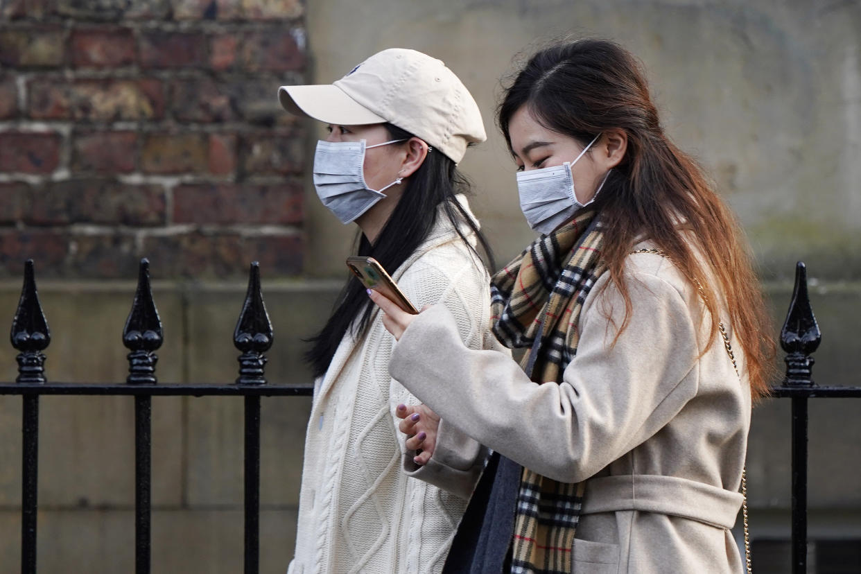 Two women wearing face masks walk through the city centre near to the Royal Victoria Infirmary where two patients who have tested positive for the Wuhan coronavirus are being treated by specialist medical workers on January 31, 2020 in Newcastle upon Tyne, England. (Getty Images)