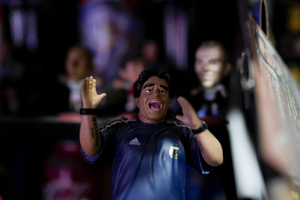 A Diego Maradona doll belonging to Osvaldo Santander sits on a shelf in a room at his home, in Buenos Aires, Argentina, Thursday, Aug. 18, 2022. Santander and his son Julian will travel to Qatar for the World Cup, their third World Cup as fans. (AP Photo/Natacha Pisarenko)