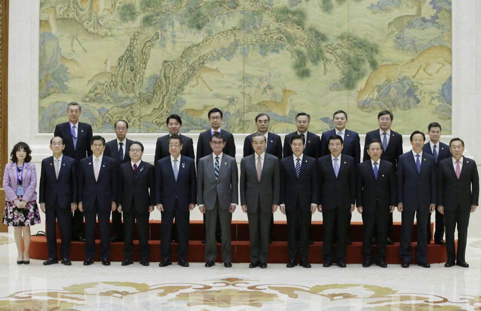 Japanese Foreign Minister Taro Kono, center left, China's Foreign Minister Wang Yi, center right, and members of Chinese and Japanese delegations attend a group photo event before the Japan-China high level economic dialogue at Diaoyutai State Guesthouse in Beijing, China, Sunday, April 14, 2019.(Jason Lee/Pool Photo via AP)