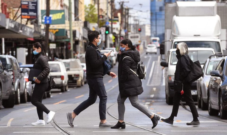 People cross a street in Melbourne during a lockdown against Covid-19.