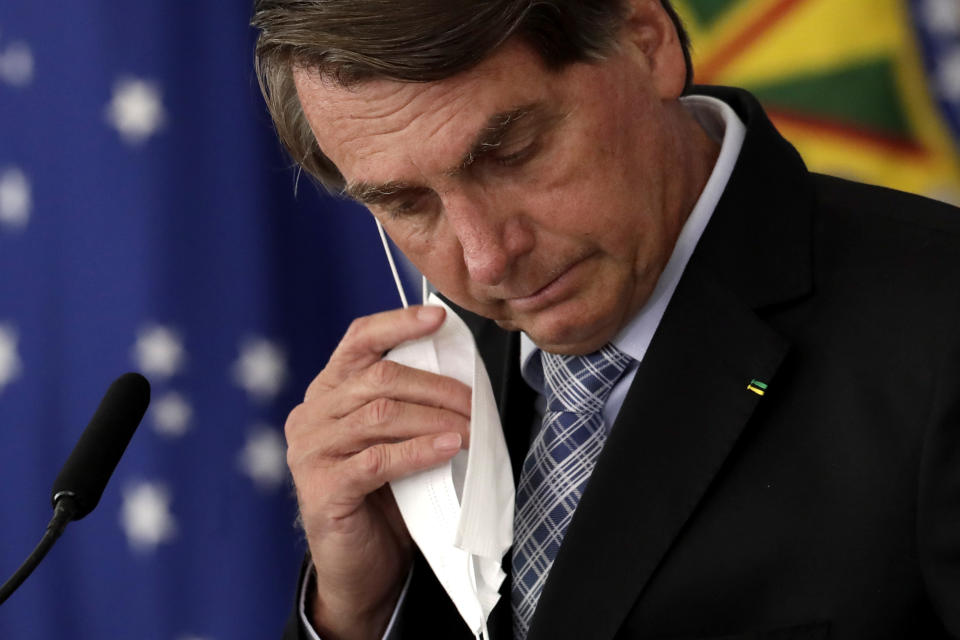 Brazilian President Jair Bolsonaro removes his mask worn due to the COVID-19 pandemic to address a ceremony to sign a law that expands the federal government's ability to acquire vaccines, at Planalto presidential palace in Brasilia, Brazil, Wednesday, March 10, 2021. (AP Photo/Eraldo Peres)