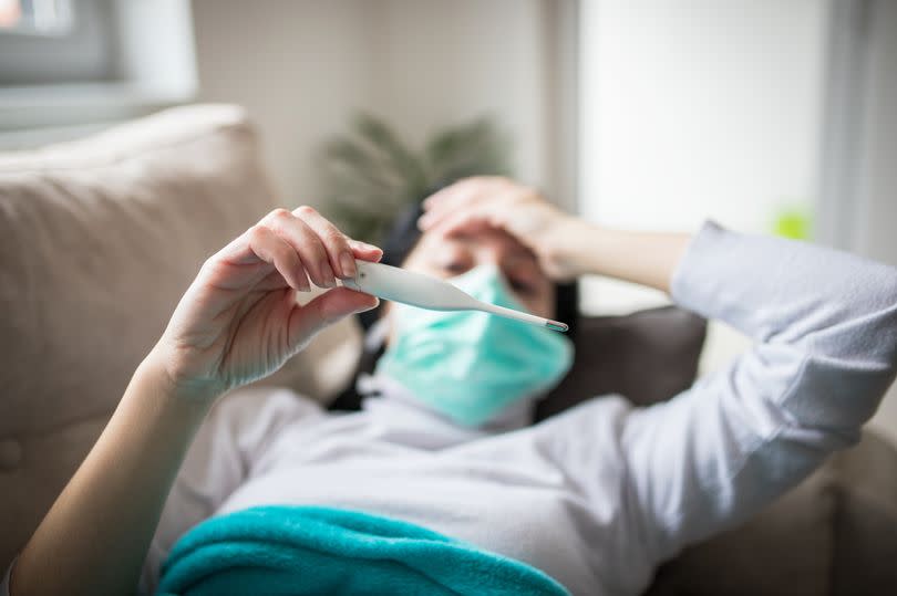 A person ill with Covid checking their temperature