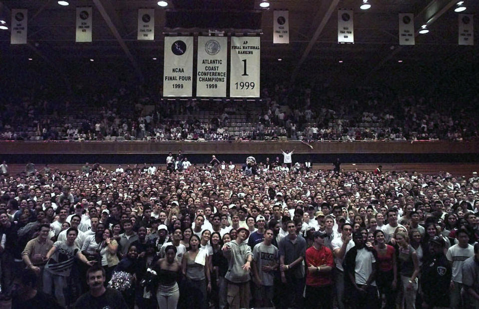 FILE - Duke students fill the floor of Cameron Indoor Stadium in Durham, N.C., Saturday, Oct. 16, 1999, as they join coach Mike Krzyzewski and the men's basketball team for a picture after Midnight Madness practice. (AP Photo/Grant Halverson, File)