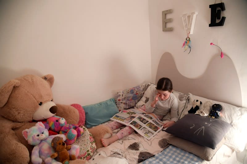 Eve, 9, reads a copy of young persons' news magazine, 'First News' before bedtime, in London