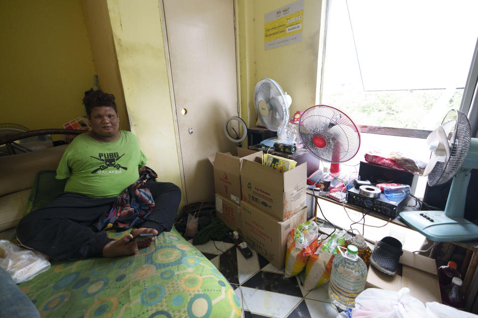 Mohamad Nor Abdullah, born without arms, sits near donated goods, right, in his rented room in Kuala Lumpur, Malaysia on July 3, 2021. When Mohamad Nor put a white flag outside his window late at night, he didn’t expect the swift outpouring of support. By morning, dozens of strangers knocked on his door, offering food, cash and encouragement. (AP Photo/Vincent Thian)