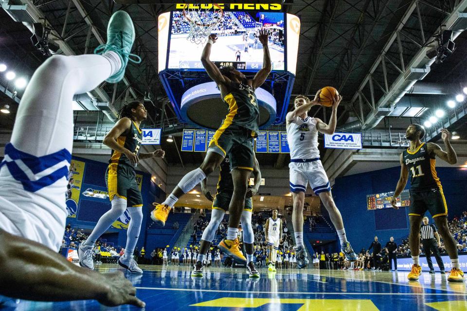 Delaware Fightin' Blue Hens guard Christian Ray (5) jumps for the basket as Drexel Dragons forward Lucas Monroe (2) jumps for the block during critical late-season CAA basketball game at the Bob Carpenter Center in Newark, Monday, Feb. 26, 2024. Drexel won 70-60.