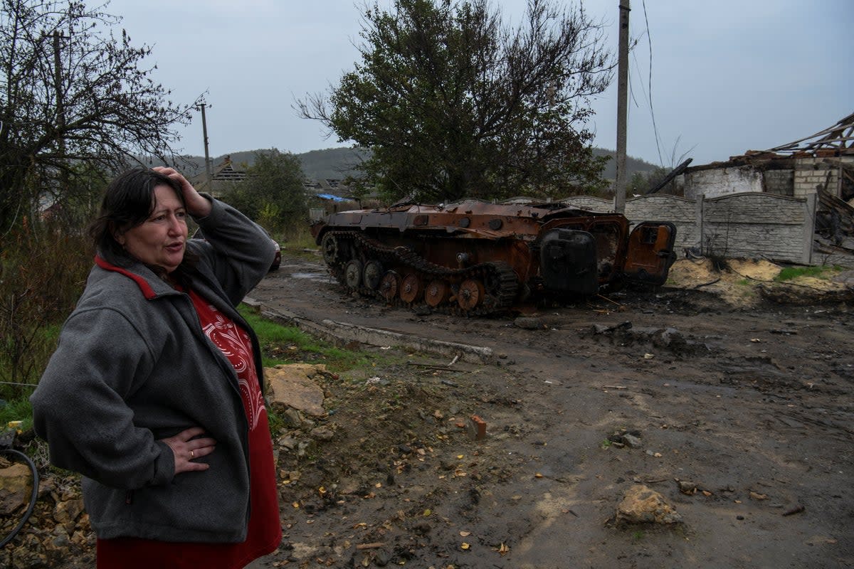 A woman next to a destroyed armoured fighting vehicle in the liberated Ukrainian village of Kamianka (REUTERS)