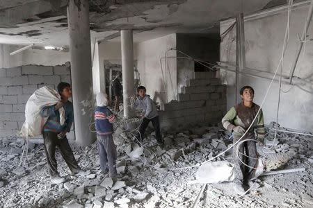 FILE PHOTO: Boys collect items from among debris at a school for the deaf and mute, destroyed in what activists said were overnight U.S.-led air strikes against the Islamic State, in Raqqa November 24, 2014. REUTERS/Nour Fourat