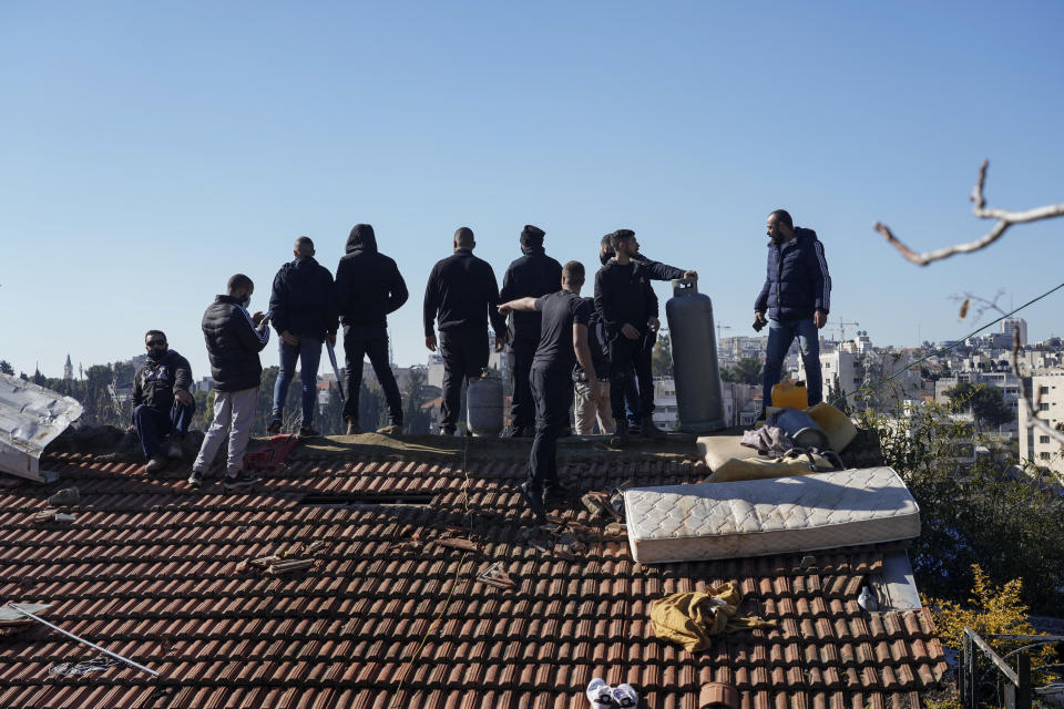 Palestinian men stand on the roof of a house with gas tanks and threaten to set them on fire should the Jerusalem municipality evict the family, in the flashpoint east Jerusalem neighborhood of Sheikh Jarrah, Monday, Jan. 17, 2022. City Hall and the police issued a joint statement saying a court ordered the family to vacate the property a year ago. (AP Photo/Mahmoud Illean)