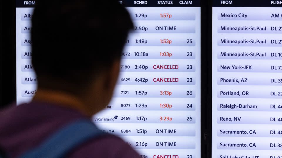 A traveler looks at a screen displaying delayed and canceled flights in Terminal 2, Delta Airlines, at Los Angeles airport, on Friday. - Etienne Laurent/AFP/Getty Images